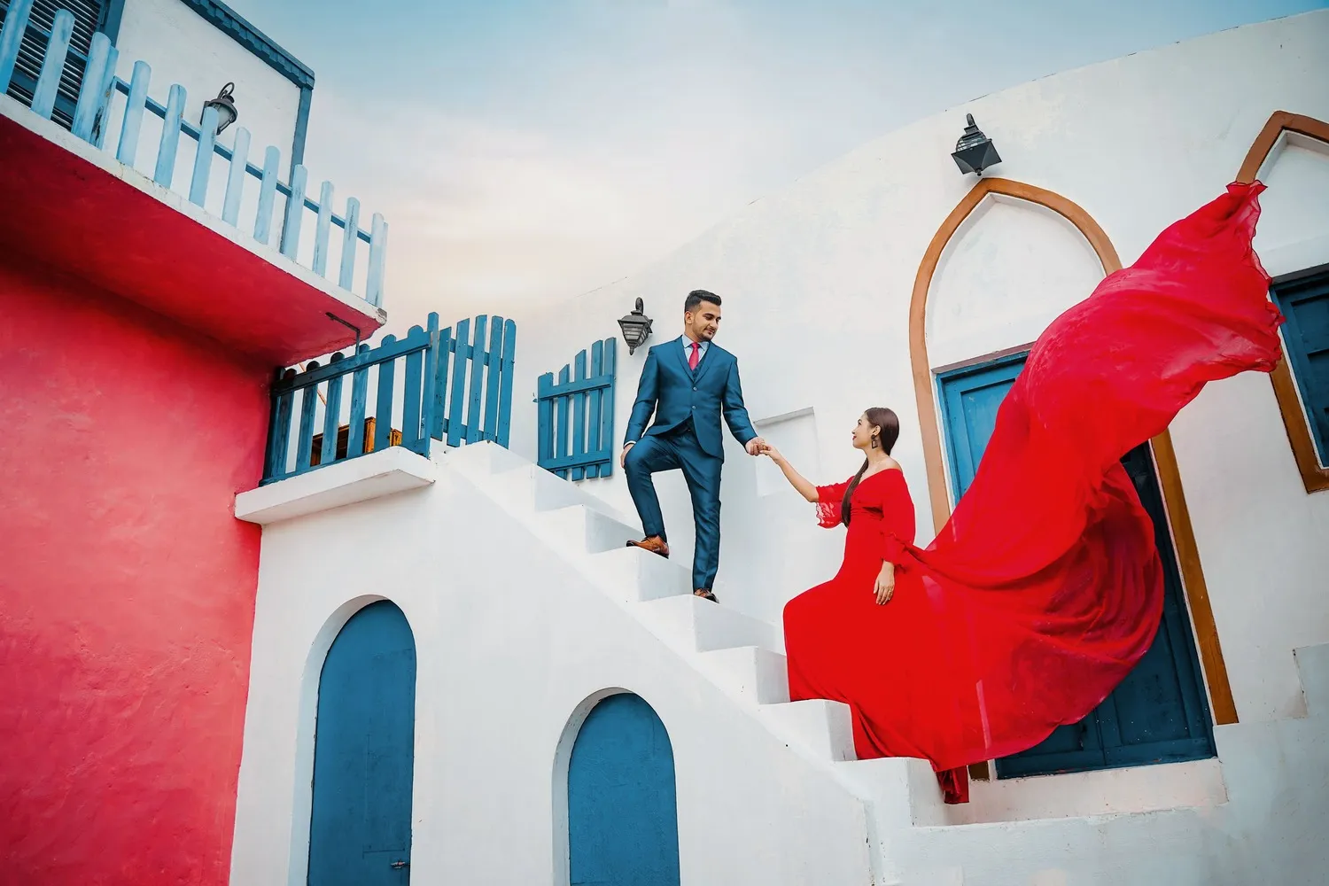 Elegant woman in flowing red dress on Mediterranean-style architecture